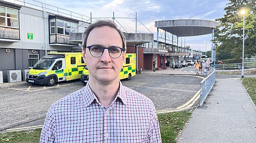 Ian Sollom standing in front of Hinchingbrooke Hospital